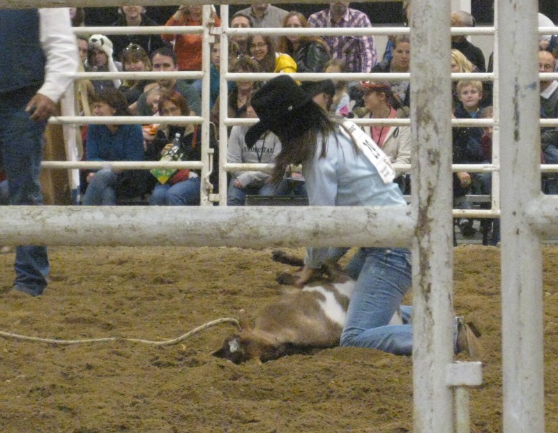 photo of rodeo cowgirl tying a goat