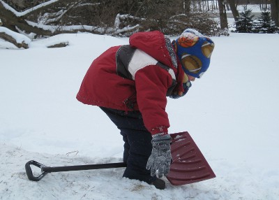 photo of a child using a shovel for a sled