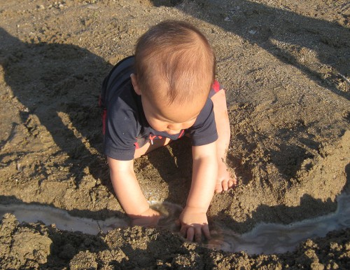 baby playing in the sand at the beach