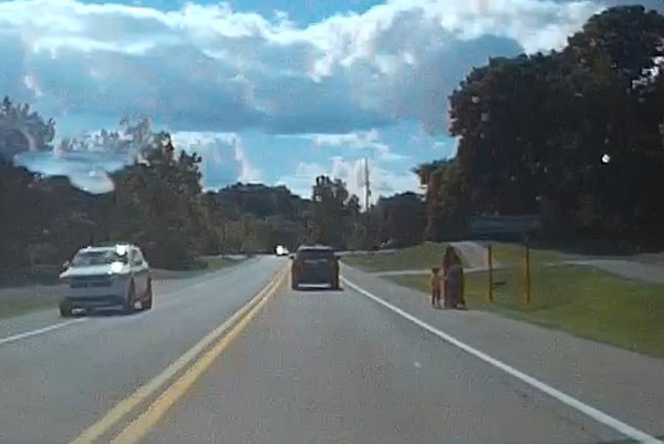 image of mom pushing a stroller and walking with another child on the side of a busy road