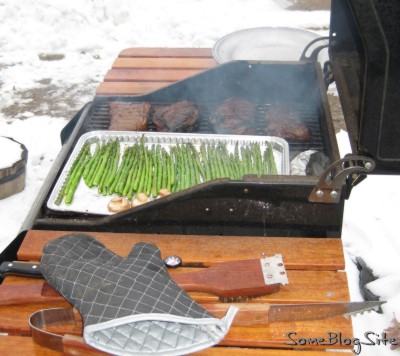 grill with steak, asparagus, and mushrooms on  a snowy day