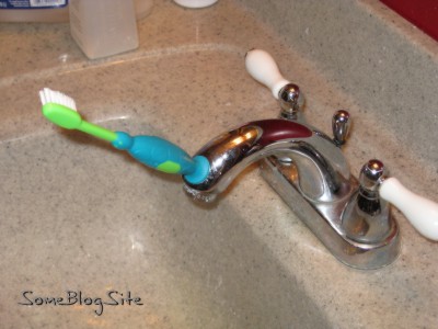 Picture of a toothbrush stuck to a bathroom faucet