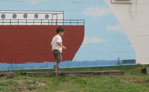 child balancing on wooden beams that mark parking spaces