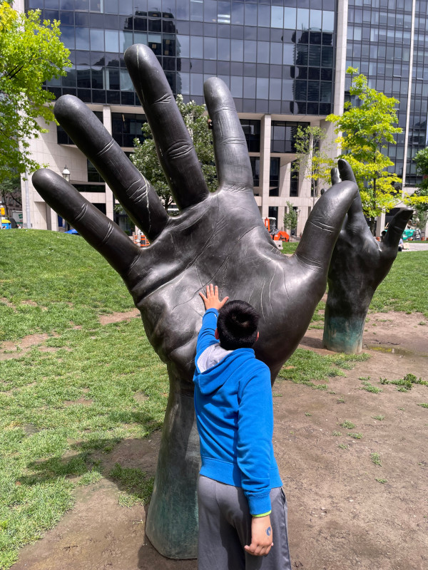 image of a kid high-fiving a sculpture of a giant hand