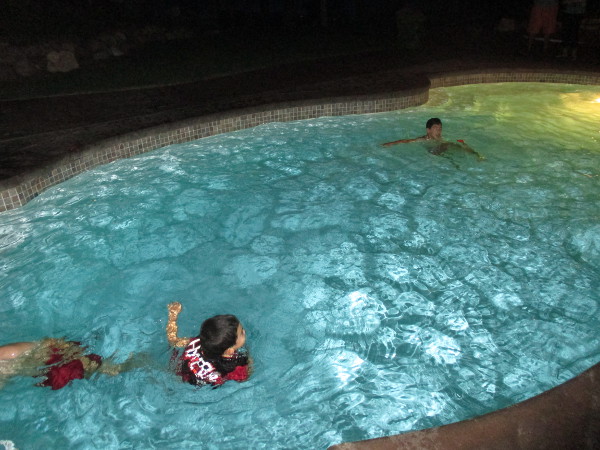photo of kids swimming in a pool at night