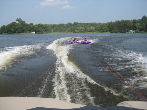 photo of boys tubing on a lake behind a speedboat