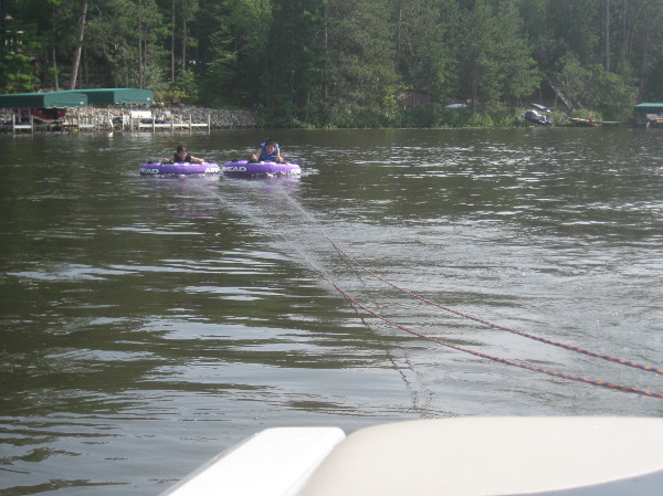photo of two kids on two tubes on a lake