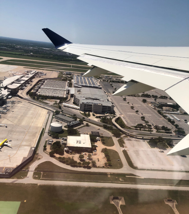 image of looking at AUS airport from an airplane with wing visible in Austin Texas