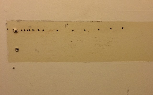 image of holes drilled in a wall to find the stud