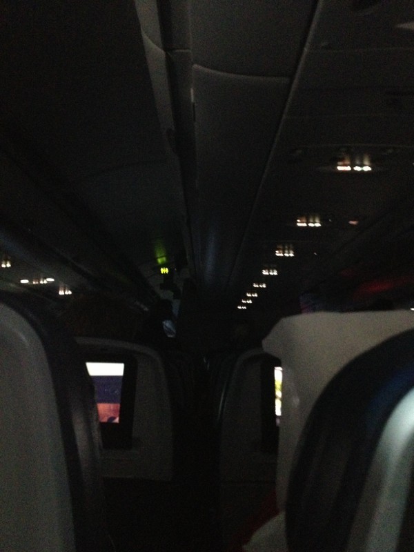 photo of the interior of an airplane that is darkened to allow people to watch their screen entertainment.